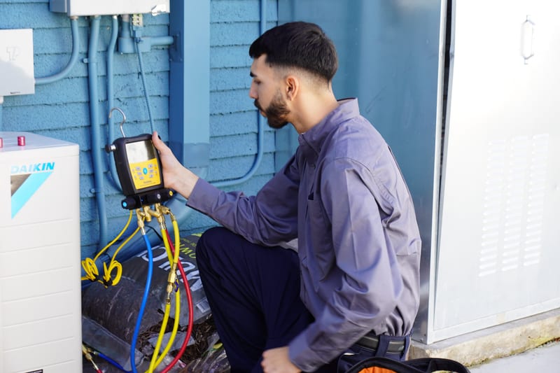 Plumber clearing a clogged kitchen sink drain with a powered auger